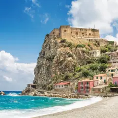 A picturesque coastal village with colorful houses clinging to a cliff, topped by an ancient castle. This is a must-see destination for anyone wondering where to go in Calabria.