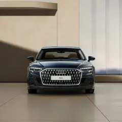 Elegancki, ciemnoniebieski Audi A8 2025 z brązowym wnętrzem prezentuje się na tle nowoczesnej architektury.