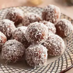 En tallrik med chokladbollar täckta av kokosflingor, redo att avnjutas. Ett enkelt chokladbollar recept för fika.