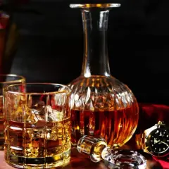 Elegancka karafka i szklanki z whisky, złoty zegarek i spinki do mankietów. Zastanawiasz się, ile cukru ma whisky?