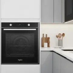 Four rosieres erreur 15 : un four encastré noir dans une cuisine moderne. Des ustensiles en bois sur le plan de travail.