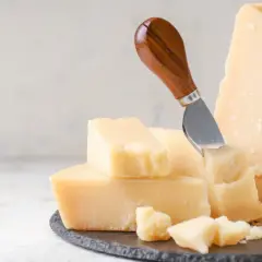 Pezzi di parmigiano reggiano, alcuni grattugiati, con un coltello. Attenzione, il parmigiano contiene lattosio.