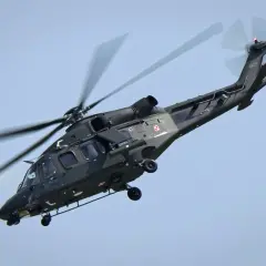 Ciemnozielone helikoptery wojskowe z polskimi szachownicami w locie.