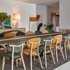 Salle à manger élégante, parfaite pour un restaurant gastronomique à Paris. Table en bois et céramique, chaises confortables aux couleurs chaudes et sombres.