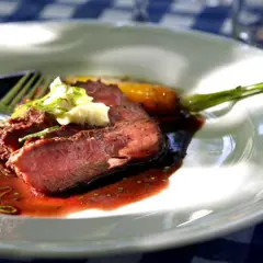 Skivad flat iron steak med perfekt medium-rare temperatur, serverad med en mustig sås och garnering.