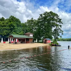 Plaża i jezioro w Szczecinku, z budynkami gastronomicznymi i ludźmi na wodzie. Idealne miejsce na letnie atrakcje.