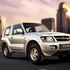 Silver Mitsubishi Montero 3.2 DID en movimiento, con edificios modernos de fondo. A pesar de su robustez, algunos propietarios han reportado problemas.