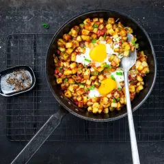 Poêle de pomme de terre oeuf, un plat réconfortant avec des dés de pommes de terre dorés et deux œufs au plat, garni de ciboule.