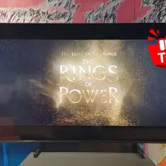 Na ekranie telewizora 1080p widać tytuł serialu "Władca Pierścieni: Pierścienie Władzy" na tle gwieździstego nieba.