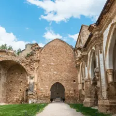 Ruinas de un antiguo convento, lugar donde se rodó Traitors España. El cielo azul con nubes contrasta con la piedra erosionada.