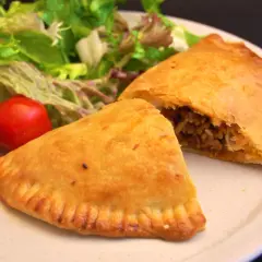 Gyldene empanadas med köttfyllning, serverade med färsk sallad och tomater. Ett perfekt recept för en smakrik måltid.