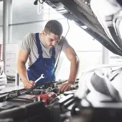 Mechanik sprawdza objawy poduszki silnika, trzymając klucz w dłoni.