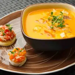 Ein cremiges Gazpacho-Rezept mit Croutons und frischen Kräutern, serviert mit kleinen Bruschettas.