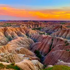 Paisaje de **las carcavas** erosionadas bajo un cielo anaranjado y azul al atardecer.