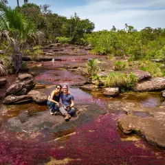 Un couple profite du Caño Cristales, la rivière aux cinq couleurs, une merveille à voir quand on se demande que faire en Colombie.