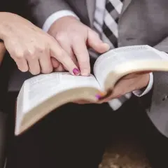Dłonie pary wskazują na tekst w Biblii, symbolizując wspólną drogę i ewangelia na ślub.