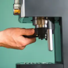Dłoń przygotowuje ekspres do zaparzenia podwójnego espresso, czyli **doppio kawa**.