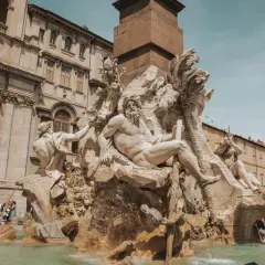 Fontanna Czterech Rzek na Piazza Navona w Rzymie, z majestatycznymi rzeźbami i turystami w tle.