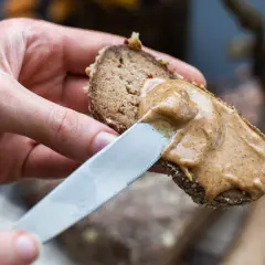 Mano spalma crema di nocciole su pane integrale. Ottima per conoscere i crema di nocciole valori nutrizionali.