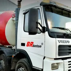 Biała ciężarówka Volvo z czerwoną obrotową beczką na beton. To jeden z rodzajów betoniarek, gotowy do transportu budowlanego.
