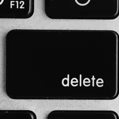Close-up of a laptop keyboard showing the '+' and '=' keys, and the prominent 'delete' key.