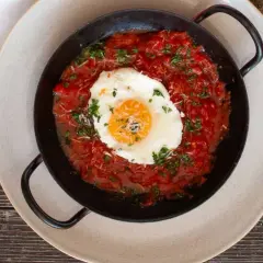 Ein Spiegelei ruht auf einer herzhaften, italienischen Tomatensauce, garniert mit Petersilie und Parmesan.