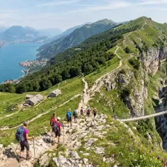 Sentiero panoramico tra i monti dell'Umbria, con escursionisti che attraversano un ponte sospeso su un profondo canyon.