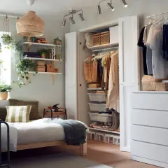 Ett mysigt små sovrum med en säng, öppen garderob och mycket grönska. Perfekt för den som gillar en ombonad stil.