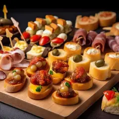 Pyszne pinchos na desce: mini kanapki z wędliną, serem, oliwkami i pomidorkami. Idealne na przyjęcie!
