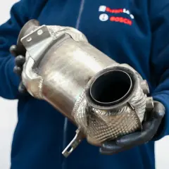 Mechanik w rękawiczkach trzyma element układu wydechowego, pokazując jak dbać o dpf.