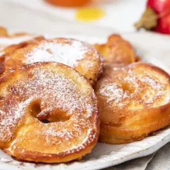 Délicieux beignets aux pommes saupoudrés de sucre glace, prêts à être dégustés.