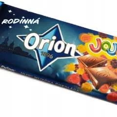 Orion Mléčná čokoláda z želkami. Kolorowe żelki w kształcie kwiatków i guzików otaczają kostki czekolady na opakowaniu.