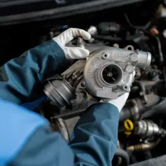 Mechanik w białych rękawiczkach trzyma turbosprężarkę, gotową do montażu, by zapewnić podwójną moc silnika dzięki twin power turbo.