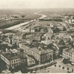 Widok z lotu ptaka na miasto z rzeką i mostami. Widać gęstą zabudowę, fabryki i wzgórza w tle. Warto przemyśl zasanie tego miejsca.
