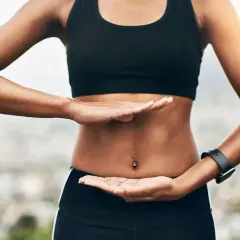 Femme pratiquant des exercices abdo hypopressifs, mains posées sur son ventre plat.