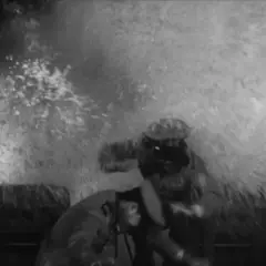 Scena z filmu fabularnego: dwóch mężczyzn w hełmach walczy z żywiołem, woda tryska na nich z ogromną siłą.
