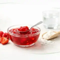 Miseczka z owocowym kisielem, łyżeczka, maliny, truskawki i skrobia. Czy kisiel jest zdrowy? Zależy od składników.