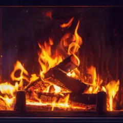 Ein Kaminfeuer lodert. Selbst wenn Holz nass wird, kann es brennen, aber es raucht und knistert mehr.