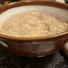 A bowl of gomo shio, a Japanese seasoning, sits on a patterned cloth.