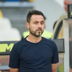 Roberto De Zerbi, mit seinem charakteristischen Blick, steht im Stadion. Seine bisherigen Trainerstationen prägen seine Laufbahn.