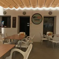 Terraza del restaurante 340, con mesas y sillas de plástico blanco bajo un toldo beige.