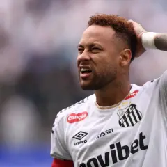 Neymar z grymasem na twarzy, trzymający się za głowę, sugeruje ból po kontuzji.