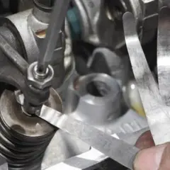 Precyzyjna regulacja zaworów silnika przy użyciu szczelinomierza. Mechanik sprawdza luz zaworowy.