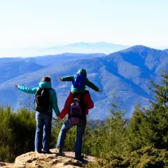 Familia disfrutando de las rutes montseny, con un niño a hombros, contemplando el paisaje montañoso.