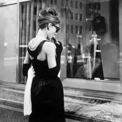 Audrey Hepburn, icónica en su vestido negro y perlas, disfruta de un pastel frente a Tiffany's.