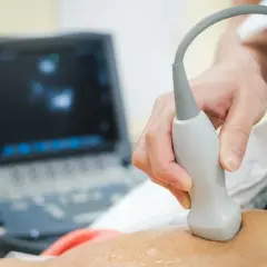 Przygotowanie do echo serca. Lekarz wykonuje badanie USG, przykładając głowicę do skóry pacjenta. Na ekranie aparatu widoczny obraz.