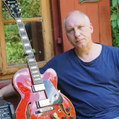 Kuba Sienkiewicz z zespołem przygotowuje się do koncertu. Czerwona gitara i wzrok pełen skupienia.
