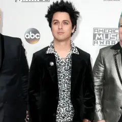 Trzech członków Green Day: Billie Joe Armstrong, Mike Dirnt i Tré Cool, pozują na czerwonym dywanie.