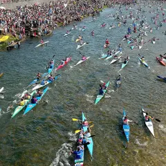 Multitudinaria fiesta de las piraguas en un río lleno de deportistas compitiendo en sus canoas.