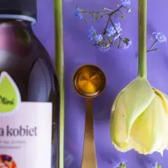Olej dla kobiet i kwiaty symbolizują naturalne sposoby na menopauzę. Złota łyżeczka z płynem sugeruje wsparcie w tym okresie.